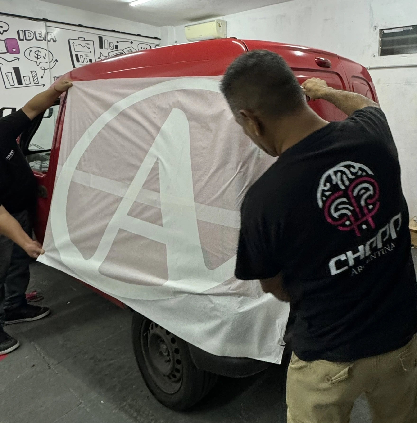 Proceso de ploteo de logo Andreani sobre camioneta roja